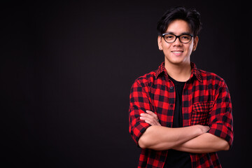 Portrait of happy young handsome Asian hipster man with eyeglasses