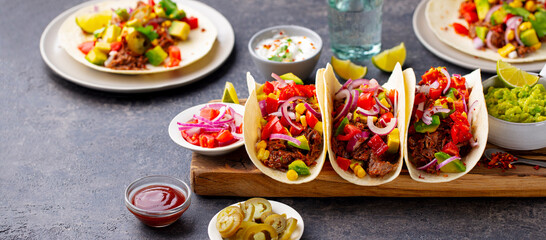 Taco with meat and vegetables on cutting board. Grey background. Close up.