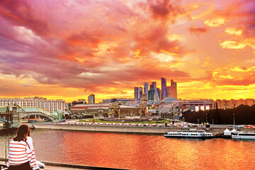 Fototapeta na wymiar downtown moscow city at sunset modern architecture landmark with girl enjoying spectacular view of red pink yellow sunset sky against business financial district skyscrapers background. Wide panorama
