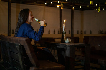 Young woman drinking a beer in a bar
