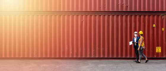 Concept of transportation and logistics business, Two technicians talking inside some harbor shipping, Foreman and docker wearing hard hats walking in the industrial container yard 21:9 aspect ratio