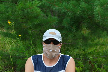 A man in a COVID-19 mask in nature in summer on a green background