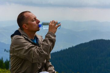 Cropped shot of a carefree young man drinking water from a bottle while going for a hike up a mountain.