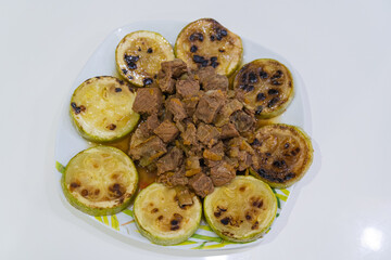 Plate with stews and zucchini on white background