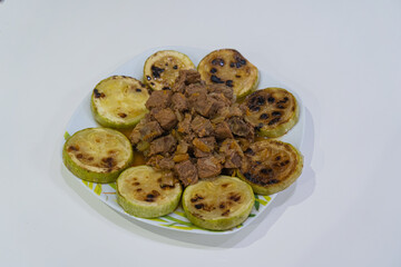 Plate with stews and zucchini on white background
