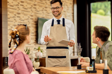 Happy waiter taking order from guests in a cafe.