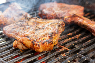 manos preparando distintos cortes en el asador y parrilla. tomahwk , rib eye , new york  tuetatons  con sal y mienta 
