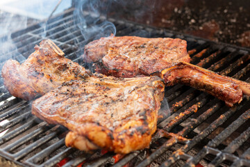manos preparando distintos cortes en el asador y parrilla. tomahwk , rib eye , new york  tuetatons  con sal y mienta 