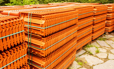 Red roof tiles are packed in standard packaging on building pallets for further transport.