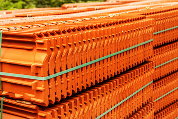 Red roof tiles are packed in standard packaging on building pallets for further transport.