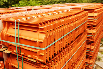 Red roof tiles are packed in standard packaging on building pallets for further transport.