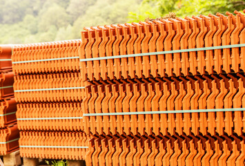 Red roof tiles are packed in standard packaging on building pallets for further transport.