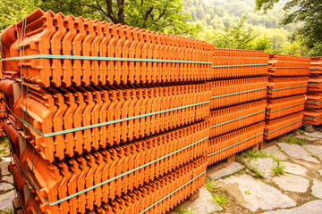 Red roof tiles are packed in standard packaging on building pallets for further transport.