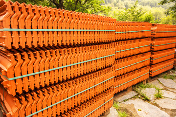 Red roof tiles are packed in standard packaging on building pallets for further transport.
