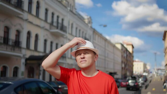 Guy tourist in a white hat walks around the city, puts on sunglasses, camera tracking