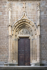 Heavy wooden door. Ancient gate on the facade of a stone building. The architecture of medieval Spain. Streets of Pamplona. Catholic Church. Massive door with a lock.