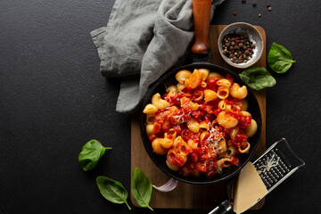 Pasta with tomato sauce and cheese in pan top view on black table