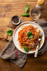 Spaghetti with red sauce on white plate top view on wooden table