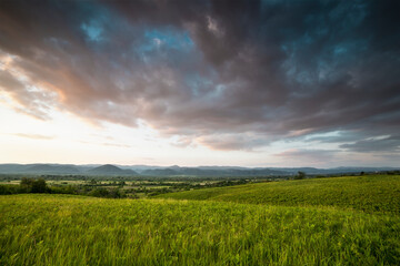 Fototapeta na wymiar Dramatic sunset over green field