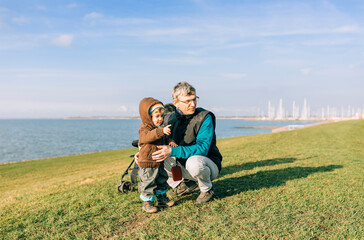 Toddler girl with grandfather on dyke of IJsselmeer