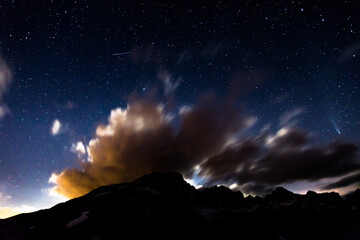 Fototapeta na wymiar Stars and clouds in the night in italian alps, including Neowise comet on the right