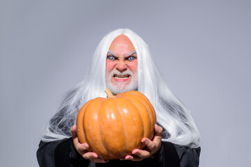 Happy Halloween. Evil wizard hold pumpkin. Man in witch hat. Traditional food. Fantasy horror...