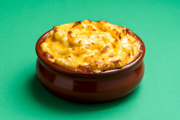 Cheese macaroni in a ceramic tray. Mac and cheese isolated on a green background.