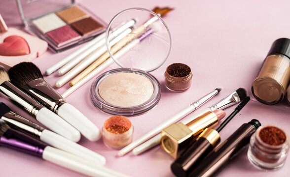 Makeup brush and cosmetics, on a pink background