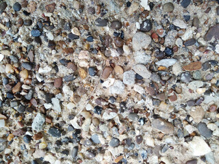 Sand background with stones of different shapes, sizes and colors.