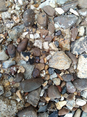 Sand background with stones of different shapes, sizes and colors.