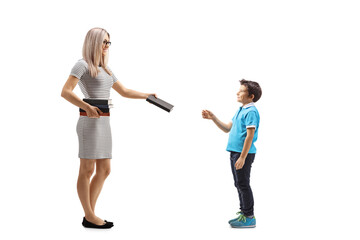 Young female teacher giving a book to a male pupil