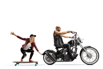 Obraz na płótnie Canvas Man riding a chopper and a young female riding a skateboard and holding onto the motorbike