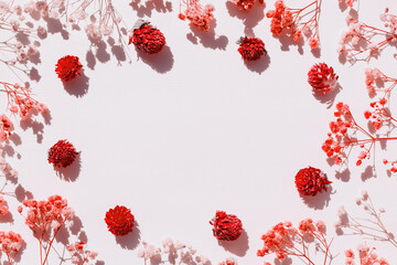 Red flower layout. Dry flowers arranged on paper. An empty space for the text in the center. Flat lay design.