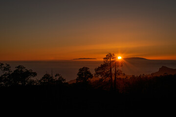 Puesta de sol con árboles y montañas