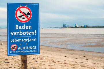 Verbotsschild an einem Strand der Nordsee mit der Aufschrift "Baden verboten! Lebensgefahr! Achtung! Eltern sind aufsichtspflichtig!" in deutscher Sprache
