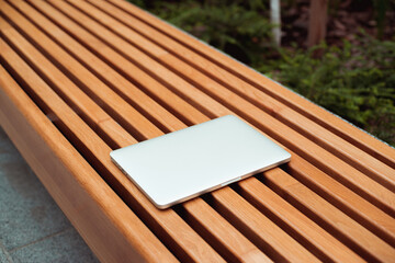 laptop lies on the bench during the day