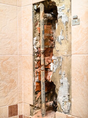 repairing of plumbing riser of heated towel rail at home - used water supply pipe in hole in wall covered by tiles