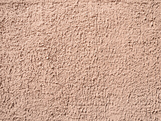 brown painted surface of coarse plastered outdoor wall lit by sun in sunny day