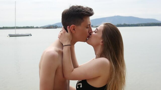 Young Man and Woman kissing on a Beach at Summer Day