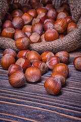 Hazelnuts in bag, vegetarian food in wooden bowls, on old wooden background