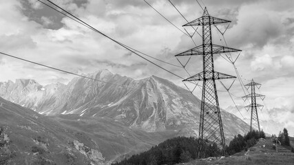 Trellis with electricity cables in a mountain environment. Dark clouds in the background. With copy space. Monochrome
