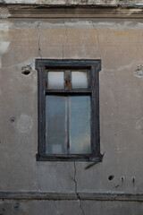 Aged closed window in wall with cracks and holes of abandoned house in Athens