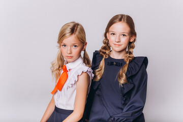 Back to school. Cute adorable caucasian blondie girls in school uniform on white background