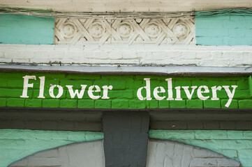 Inscription flower delivery on green background of brick
