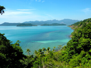 Herrliche Aussicht von Berg aufs türkisfarbene Meer und Blick auf umliegende Berge mit Bäumen