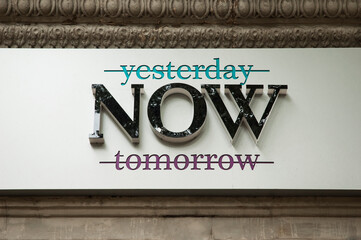 Generic advertisement for the moment of now with crossed out words yesterday and tomorrow on historic facade