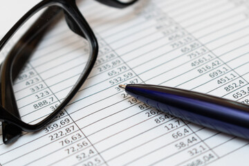 Glasses and a ballpoint pen are on the table in reports. Financial concept