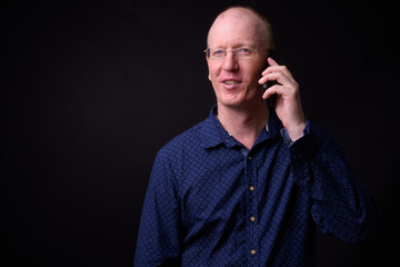 Portrait of happy bald businessman with eyeglasses talking on the phone