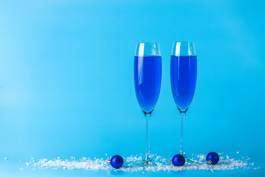 Two wineglasses of blue champagne  on a blue background with Christmas an New Year decor. Shallow depth of the field, copy space for you text.