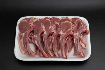 Raw lamb chops (cutlets) in a white styrofoam container isolated on black background with copy...